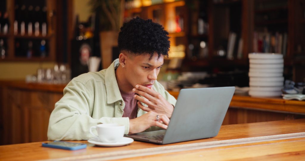 Mieshenkilö käyttää kannettavaa tietokonetta pöydän ääressä.