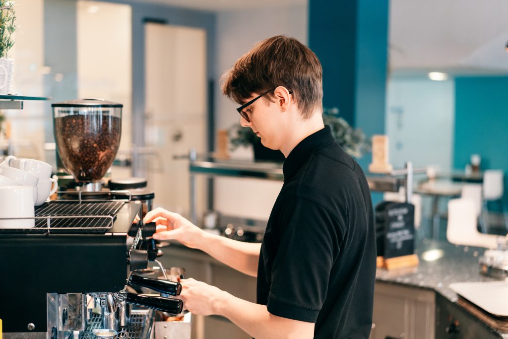 Nuori barista tekee kahvia kahvilassa.