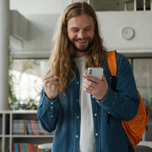 mieshenkilö katsoo innostuneena puhelinta